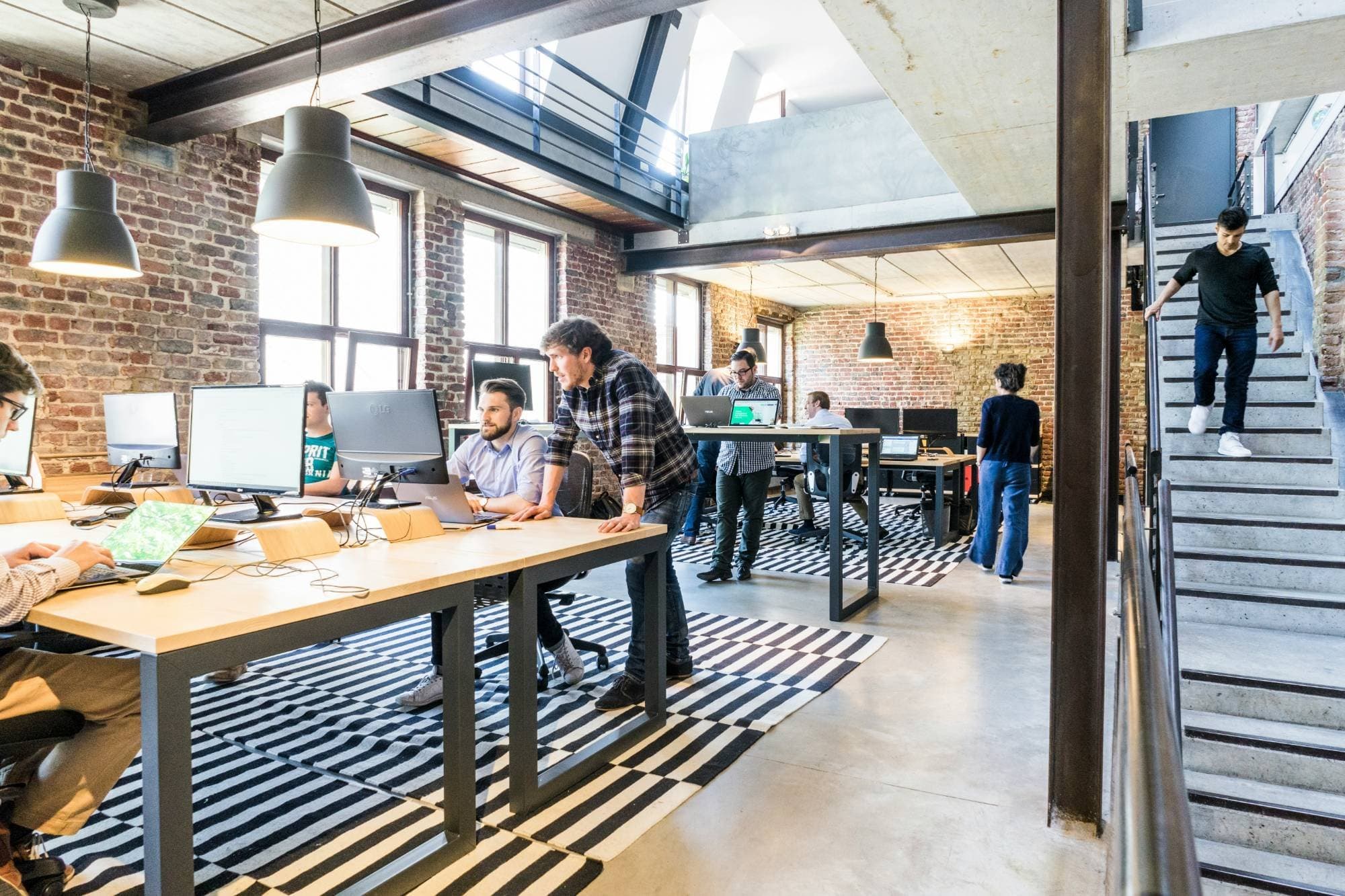 Equipo trabajando en una oficina luminosa de estilo industrial, con mesas amplias y arquitectura contemporánea.